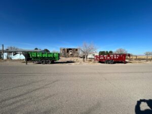 Two dump trailers from Easy Load Disposal El Paso parked at a junk removal site with old structures in El Paso, TX.