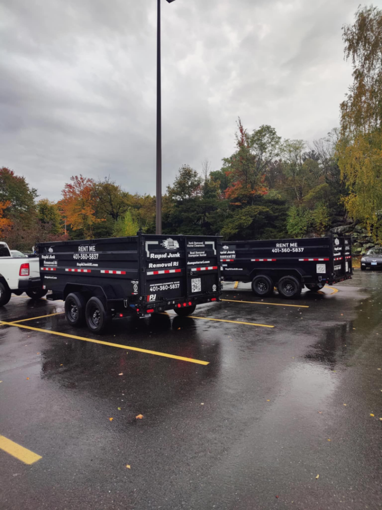 Two empty dumpster trailers from Dumpsters RI.com - Dumpster Rentals RI parked in a commercial parking lot in Rhode Island.