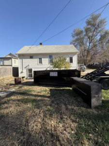Two H & H Dumpster Rental dumpsters, one on a truck and one on the ground, in a residential backyard in Rootstown, OH.