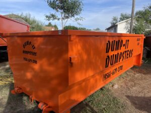 Two orange Dump-IT Dumpster Rentals LLC dumpsters placed in a backyard in Laredo, TX, ready for a junk removal project.