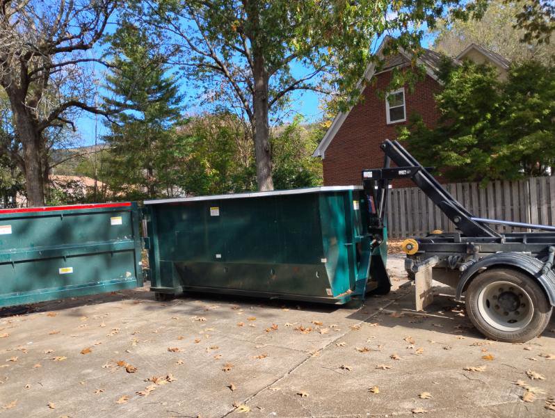 Two green dumpsters, one being loaded onto a truck, by Beetles Dumpsters Rental & Junk Removal in Huntsville, AL.