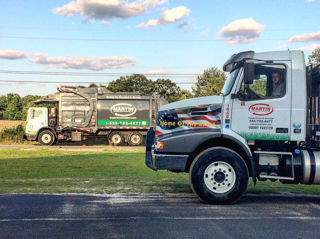 Two Martin Environmental garbage trucks on a road, ready for waste collection in Dothan, AL.