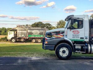 Two Martin Environmental garbage trucks on a road, ready for waste collection in Dothan, AL.