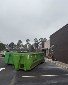 Two large green dumpsters from Top Line Dumpsters LLC placed in a commercial parking lot in Hammond, LA.