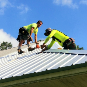 Two handymen from ABOVE & Beyond Roofing installing a new metal roof on a house in Metairie, LA.