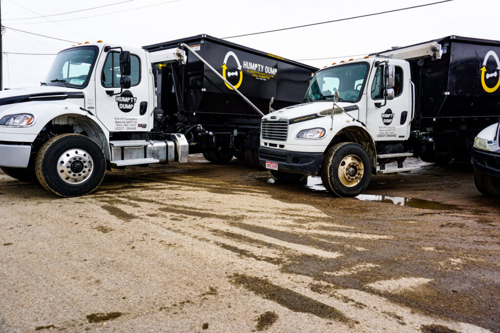 Two Humpty Dump Roll-Offs & Dumpsters trucks with roll-off dumpsters parked side-by-side in Commerce City, CO.