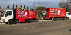 Two Great White Junk Removal trucks parked at a job site with debris visible, ready for removal in San Francisco, CA.
