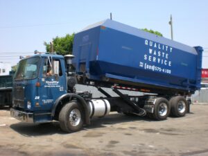 Two junk removal trucks, one with a large dumpster, from Quality Waste Service, Inc. in Los Angeles, CA.