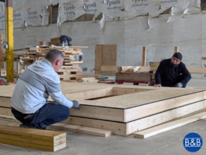 Two men assembling a wooden frame or panel, performing construction work for Buildings & Builders in Columbus, OH.
