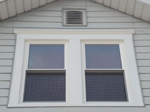 Two new windows with white trim and blinds installed on the upper level of a house by Hack's Construction & Window Co in Fishers, IN
