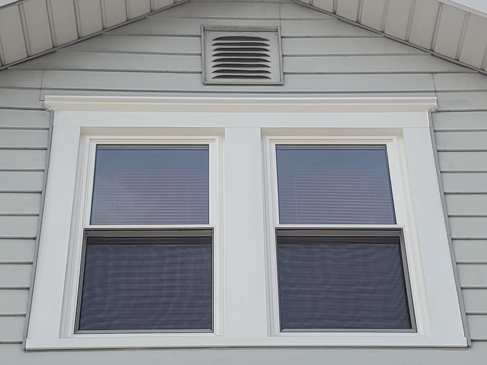 Two new windows with white trim and blinds installed on the upper level of a house by Hack's Construction & Window Co in Fishers, IN