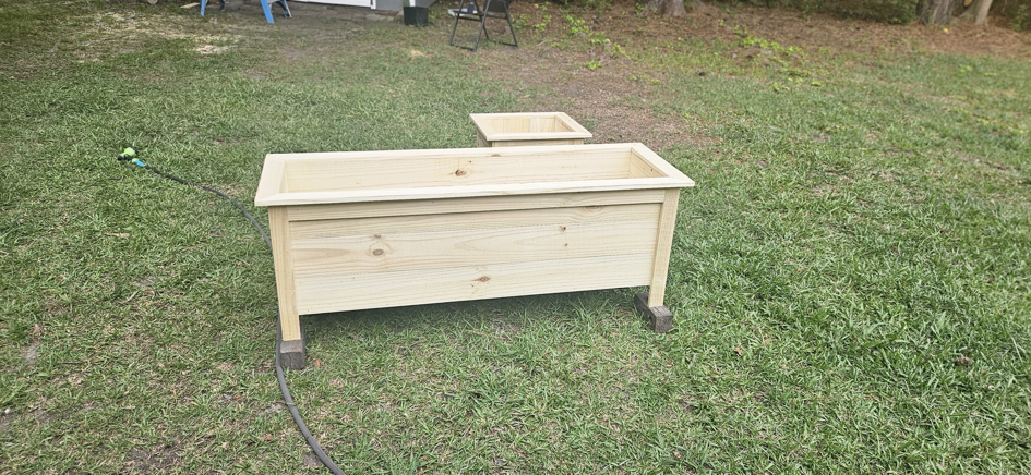 Two newly constructed wooden planter boxes placed in a grassy yard by Turn Key Of Charleston in North Charleston, SC.