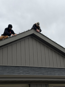Two people installing Christmas lights on a residential roof, a service provided by JP Handyman Wyo in Sheridan, WY