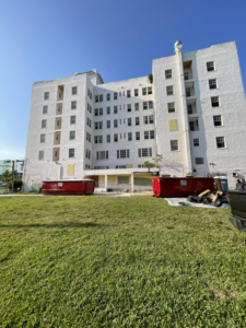 Two red dumpsters on site for a junk removal project outside a large building by Dumpster Rental Florida in West Park, FL.
