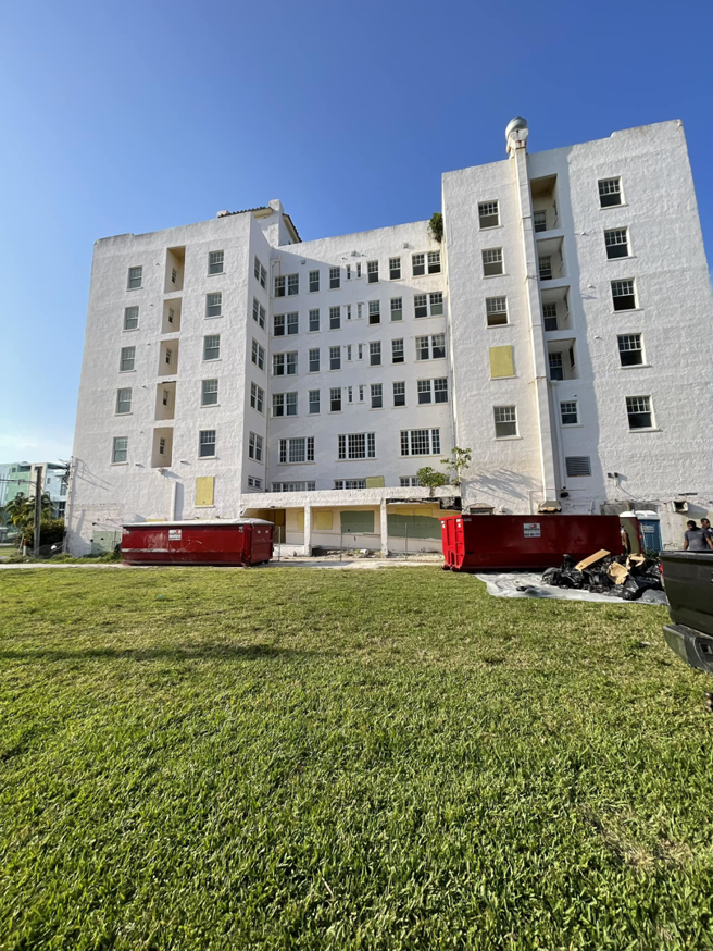 Two red dumpsters on site for a junk removal project outside a large building by Dumpster Rental Florida in West Park, FL.