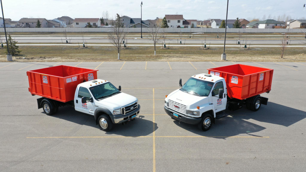 Two roll-off dumpster trucks from Red River Removal parked in West Fargo, ND, ready for junk removal services.
