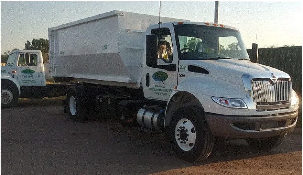 Two white roll-off trucks, part of the fleet for junk removal services, parked at EM Enterprises, Inc. in Cheyenne, WY.