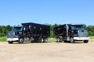 Two Delta Waste Solutions roll-off trucks with dumpsters, showcasing junk removal capabilities in Hattiesburg, MS.