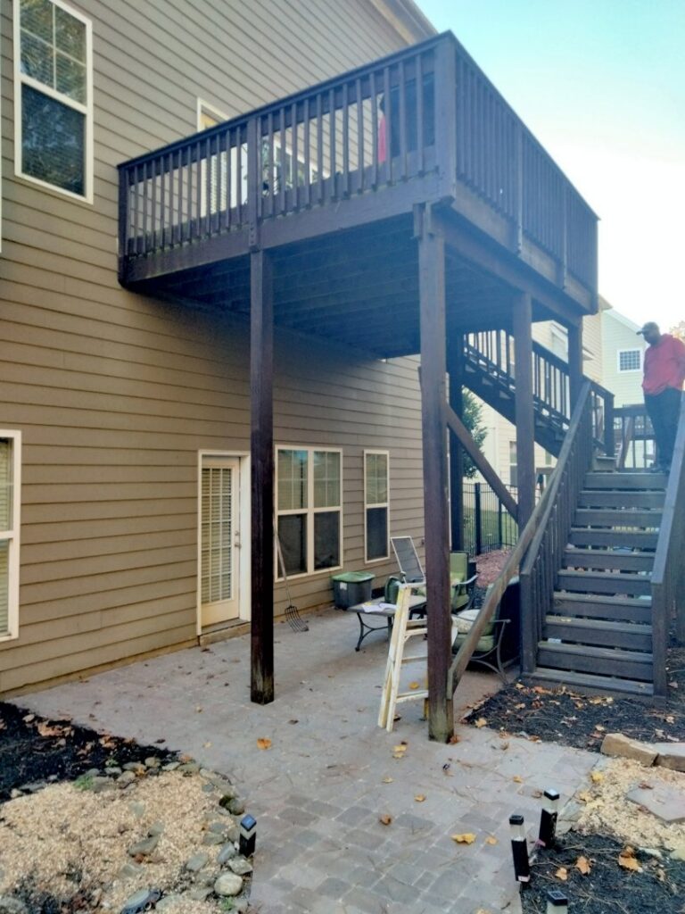 A two-story wooden deck and paved patio area, maintained by Mels Haul & Junk Removal in Raleigh, NC.