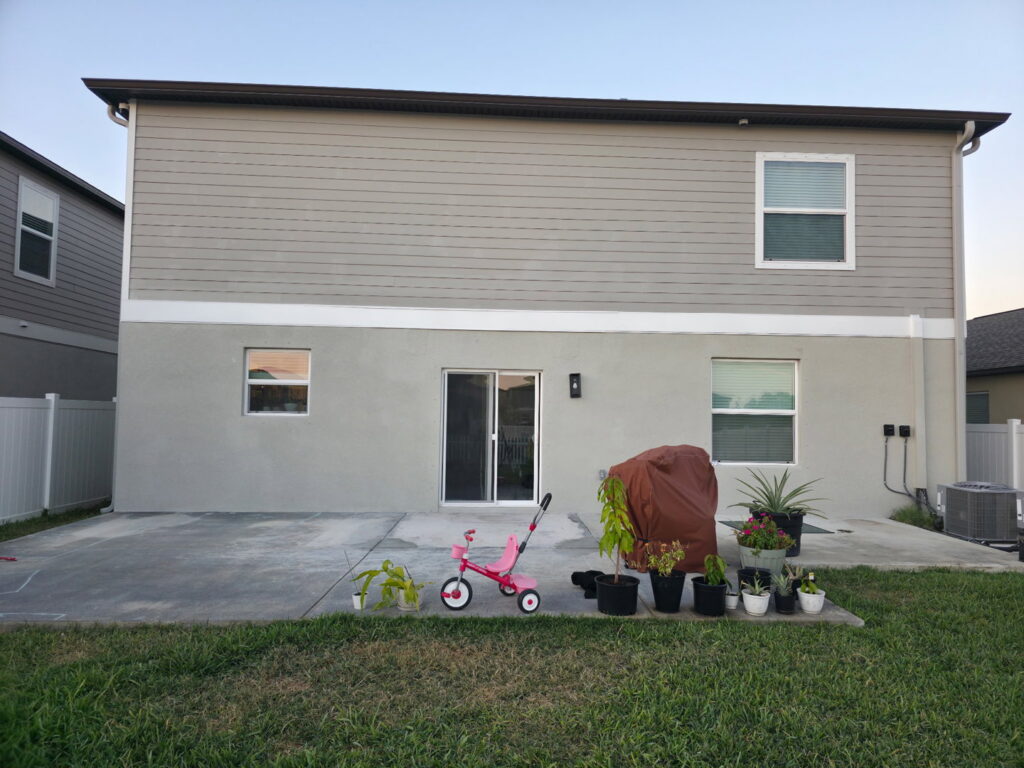 The rear of a two-story house with new siding, stucco, and windows, completed by Alejandro Melo Contractor corp in Tampa, FL.