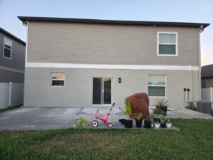 The rear of a two-story house with new siding, stucco, and windows, completed by Alejandro Melo Contractor corp in Tampa, FL.