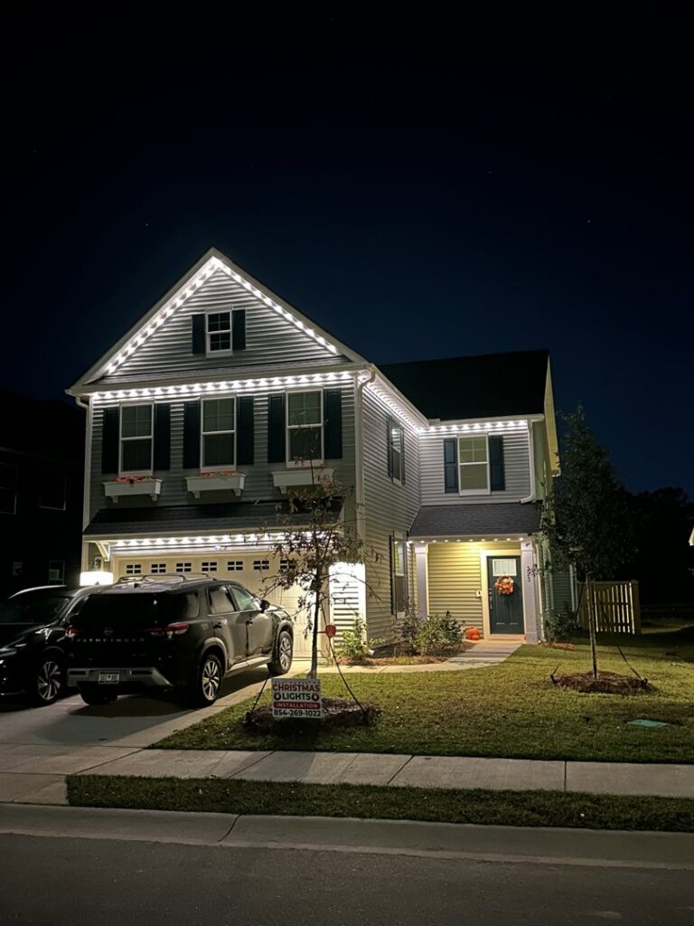 A two-story house with white Christmas lights installed on the roofline by Lights Made Easy of Charleston, SC