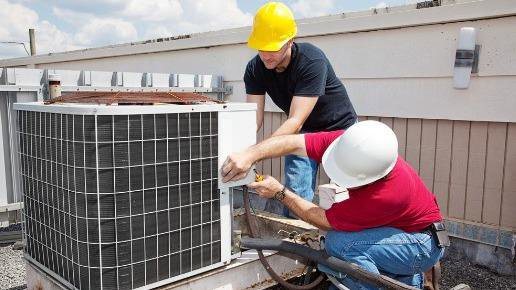 Two technicians in hard hats working on a large commercial rooftop air conditioning unit for Advanced Mechanical Contractors, Inc. in Nashville, TN.