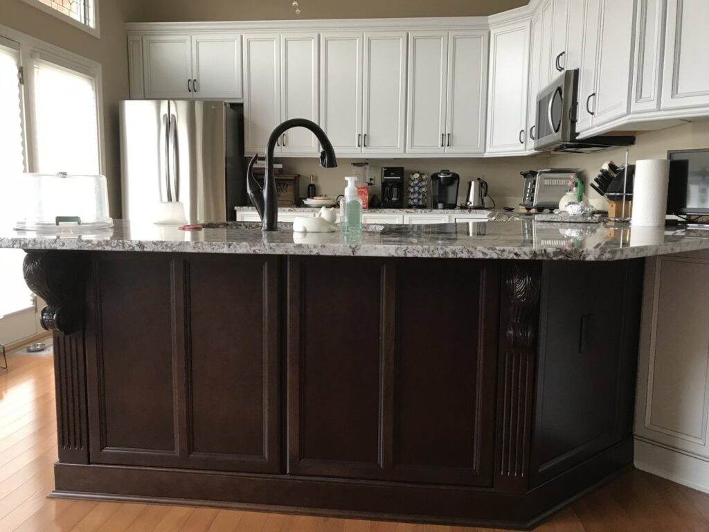 A kitchen featuring two-tone cabinets with a dark brown island and white upper cabinets by Cincinnati Cabinet Refacing in Cincinnati, OH.