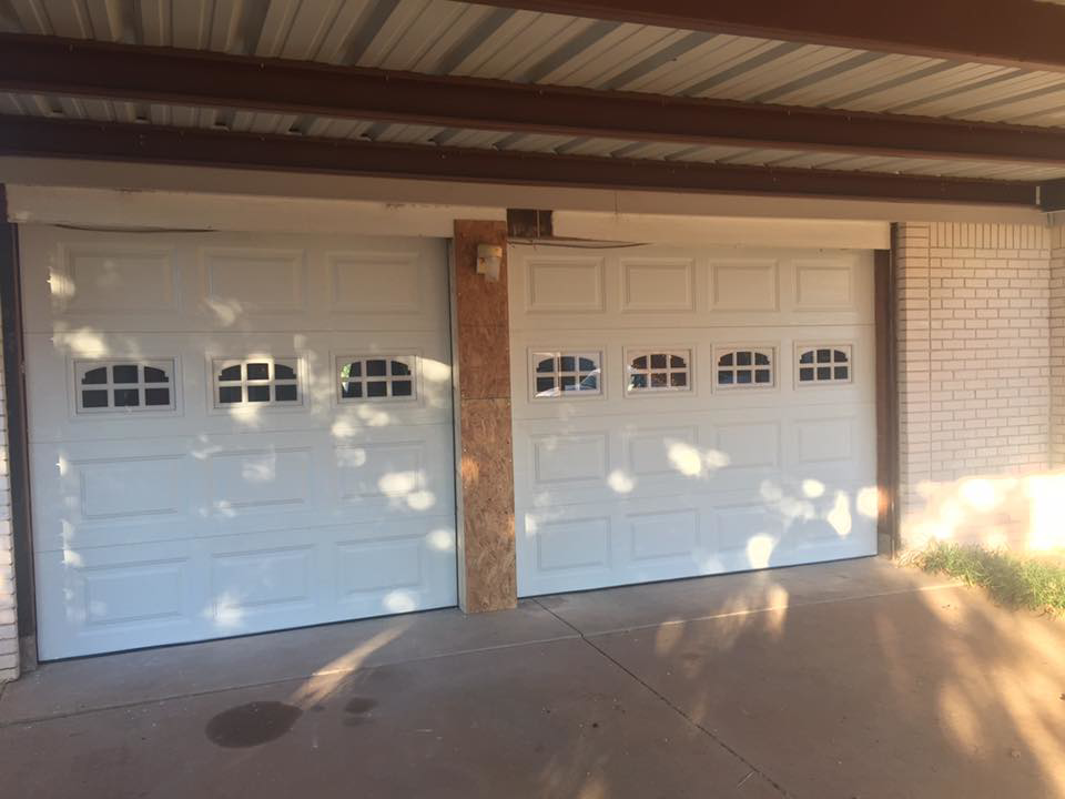 Two white garage doors with decorative windows installed on a house by Big Red Overhead Door, LLC in Moore, OK.
