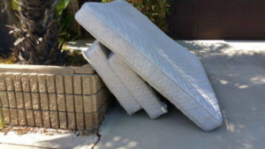 Two white mattresses leaning against a concrete planter, awaiting disposal by Omaha junk Removal and Hauling Service in Omaha, NE.