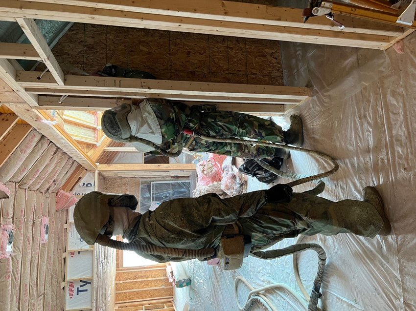 Two workers from Insulation Man applying spray foam insulation to interior walls of a building in Chesterfield, MI.