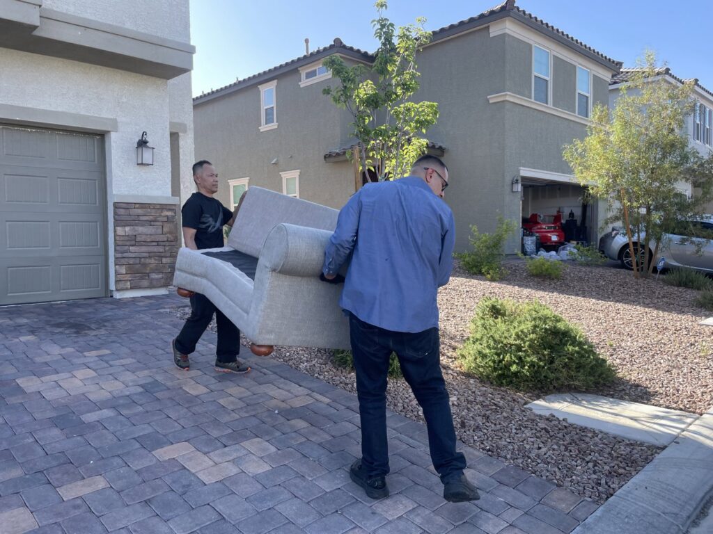 Two Tidy Toss workers carrying a sofa out of a house for removal in Las Vegas, NV