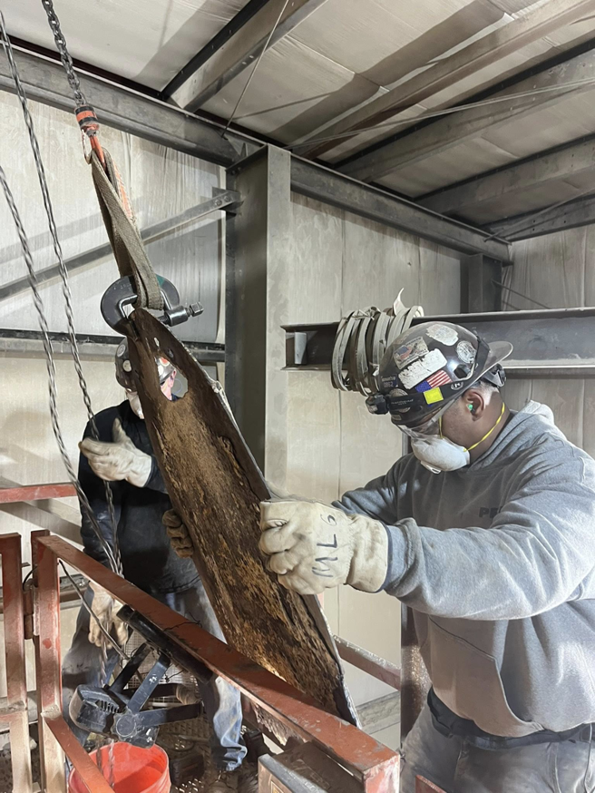 Two workers from The Price Erecting Co. installing a heavy machinery part in Milwaukee, WI.