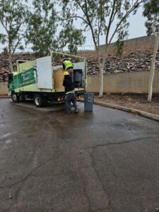 Two Skunky's Junk Removal workers loading a large bale and other items into their truck in Tempe, AZ.