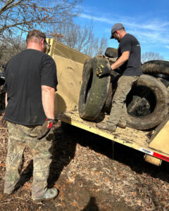 Two workers from Curry Dumpster Rentals LLC loading old tires into a dumpster during a junk removal service in Southaven, MS.
