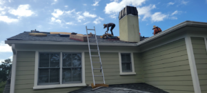 Two workers performing a roofing project with a ladder for WITTE CONSTRUCTION LLC in Mount Pleasant, SC.