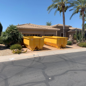 Two yellow dumpsters placed in a residential driveway for junk removal by AZ Dumpster Rentals in Surprise, AZ