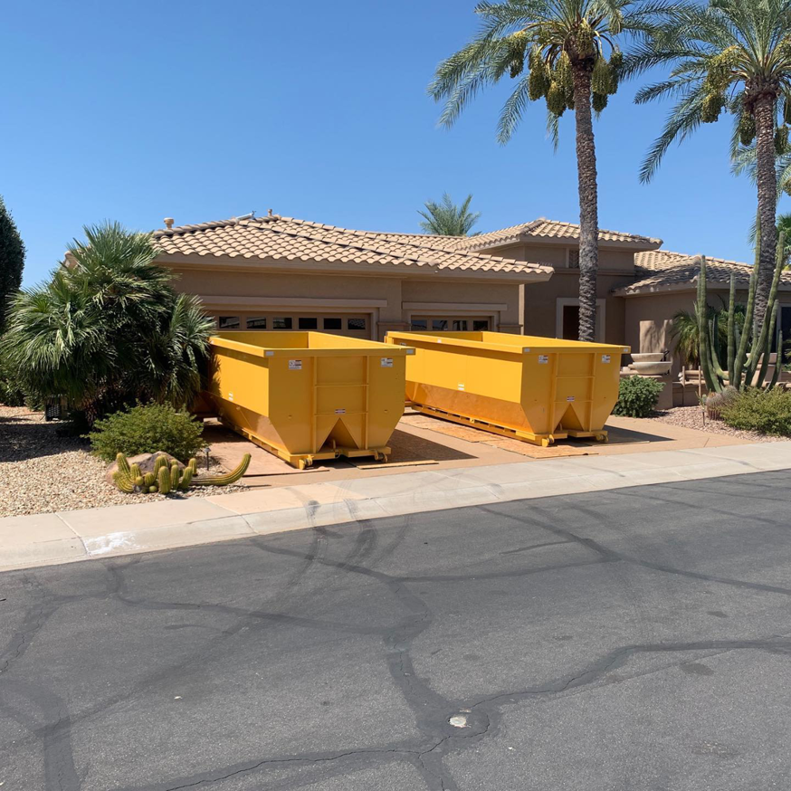 Two yellow dumpsters placed in a residential driveway for junk removal by AZ Dumpster Rentals in Surprise, AZ