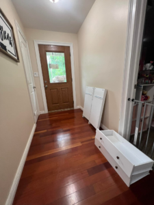 Unassembled white cabinet parts and drawers laid out on a hardwood floor, ready for assembly by Assembly Required in Summerville, SC.