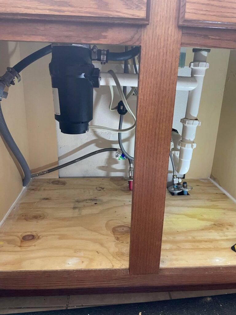 Under-sink plumbing with a garbage disposal unit, demonstrating plumbing services by FES handyman services LLC in Boise, ID.