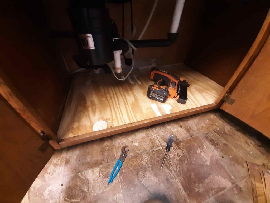 Under a kitchen sink showing plumbing and garbage disposal installation by Victor White Handyman in Long Beach, CA