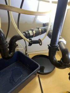 Under-sink plumbing repair with a blue tray catching water, performed by Titan Handyman Services in Lewes, DE