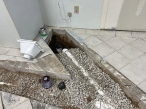 An open trench in a tiled floor showing new PVC drain pipes installed by Read Plumbing LLC in Ankeny, IA.