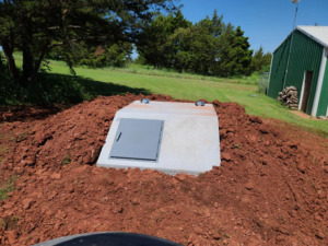 A newly installed underground concrete storm shelter surrounded by fresh dirt by Taylor Storm Shelters in Stillwater, OK.