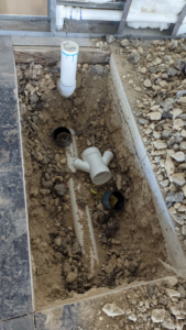 Underground plumbing pipes being installed in a trench during a construction project by Rivera Services in Chandler, TX.