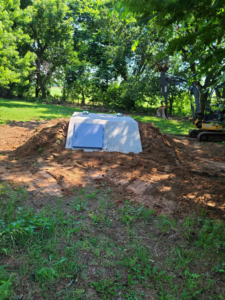An underground storm shelter installation in progress with an excavator by Taylor Storm Shelters in Stillwater, OK.