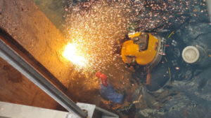 An underwater diver performing welding or cutting work with sparks flying, demonstrating specialized services by Zion Marine in Kingsport, TN.