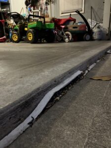 A clear view of an uneven concrete slab at a garage entrance, a common repair job for A1 Concrete Leveling Cincinnati/NKY in Cincinnati, OH.