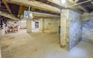 An unfinished basement with exposed beams and rough walls, a potential project for Foundation Repair and Waterproofing in Philadelphia, PA.