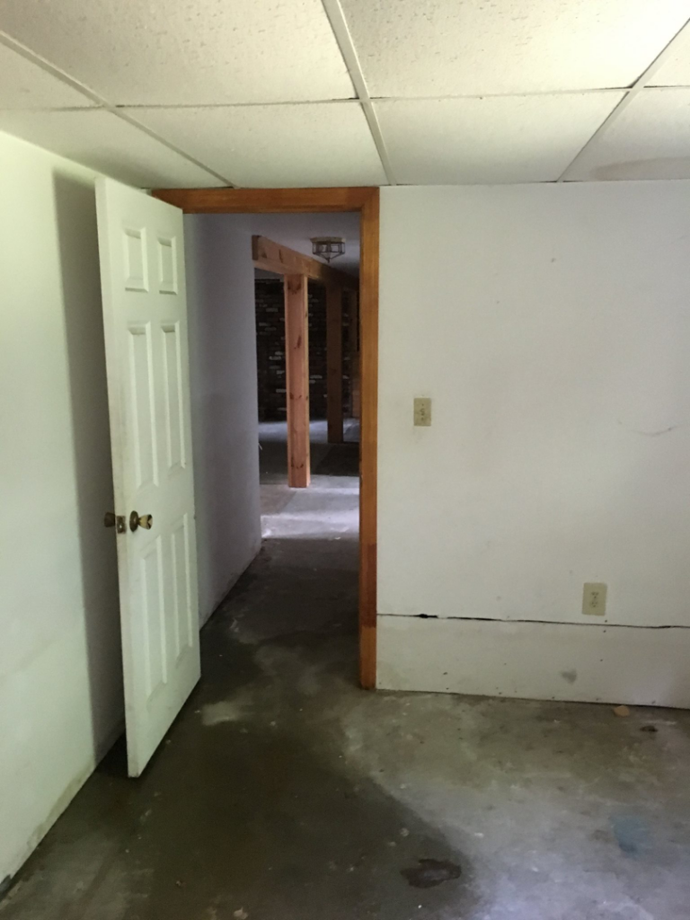 An unfinished basement room with a drop ceiling and exposed doorway, ready for handyman work by Lemelin General Contracting in Fall River, MA.